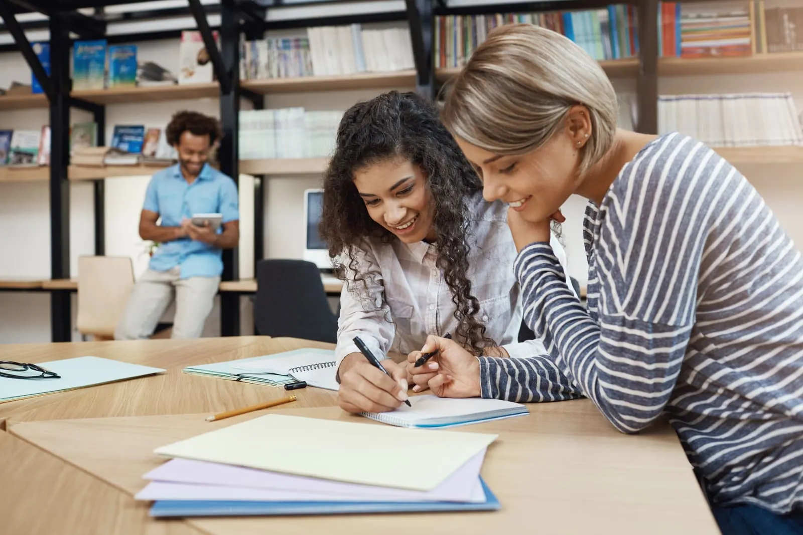 An adult helping a student with a worksheet at a classroom table