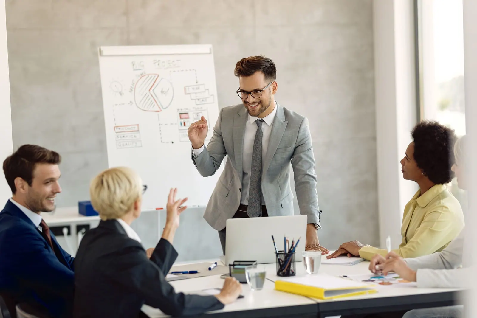 An educator presenting a plan on a whiteboard to a group of colleagues