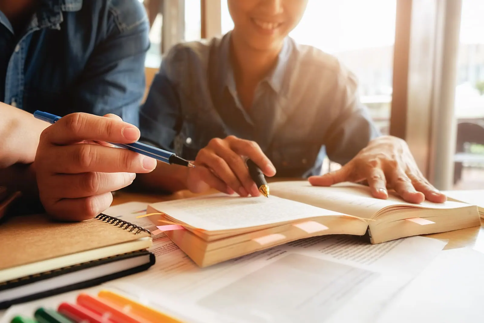An adult student taking notes from an open textbook at a desk
