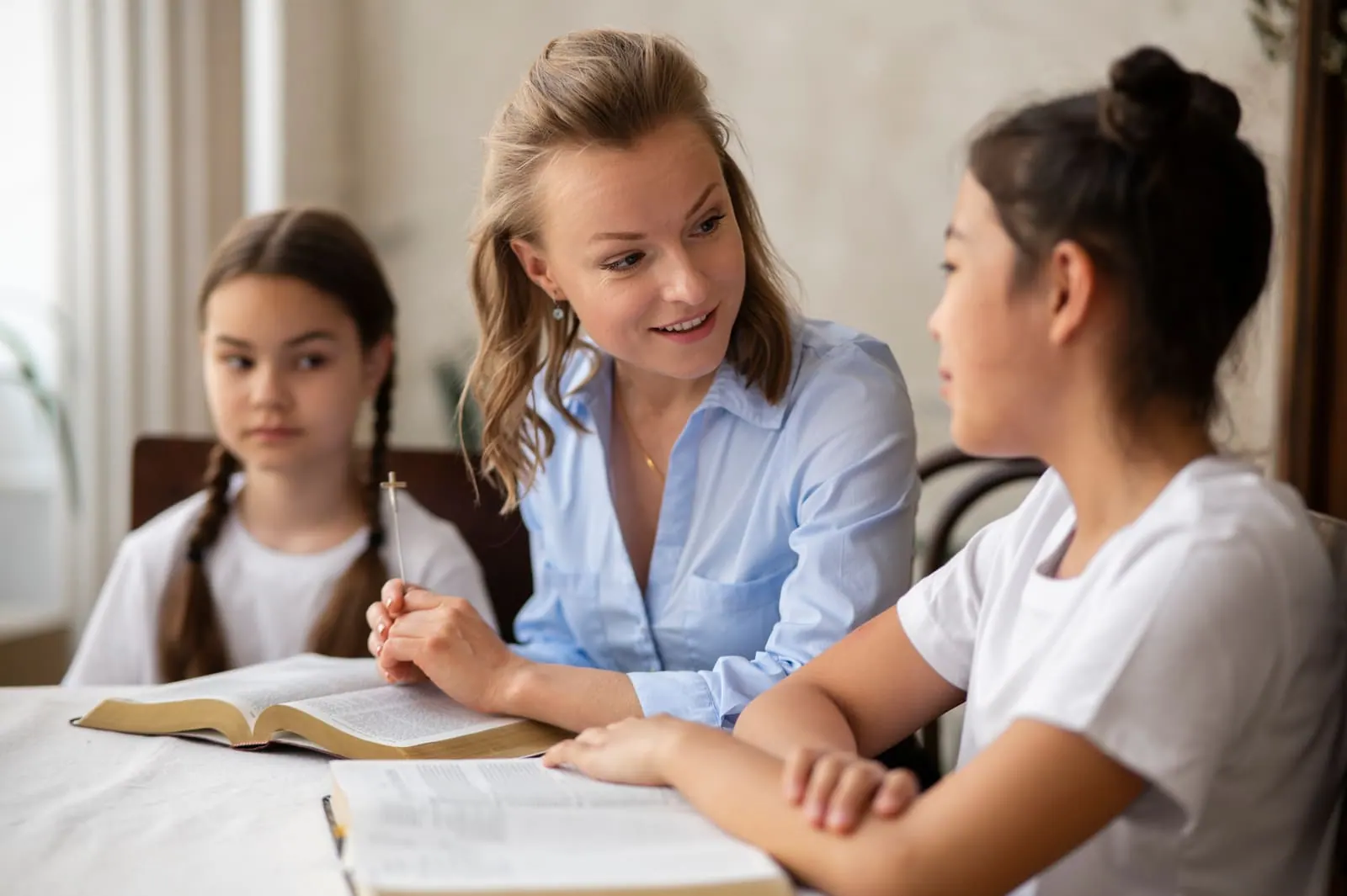An adult talking with two students at a table