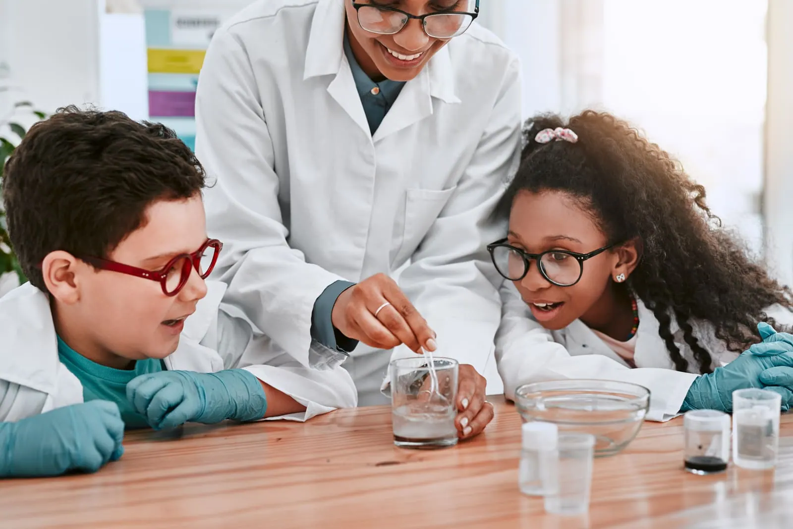 A science teacher in a lab coat running an experiment with students