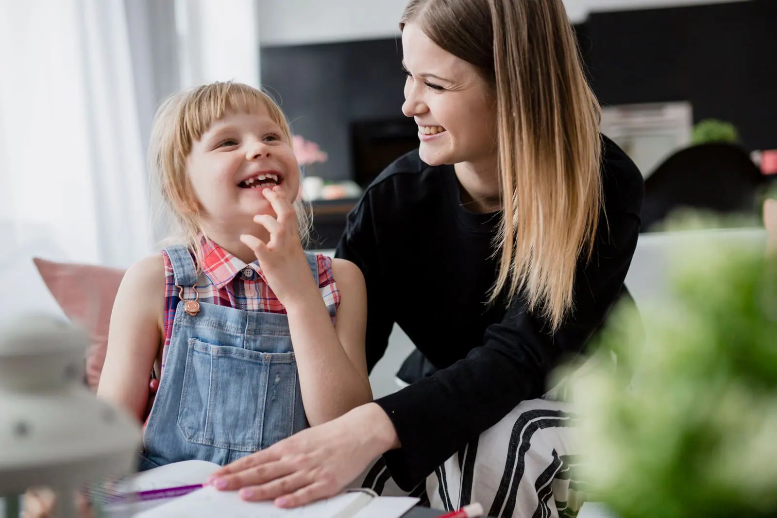 A teacher and a young girl laughing together at a table